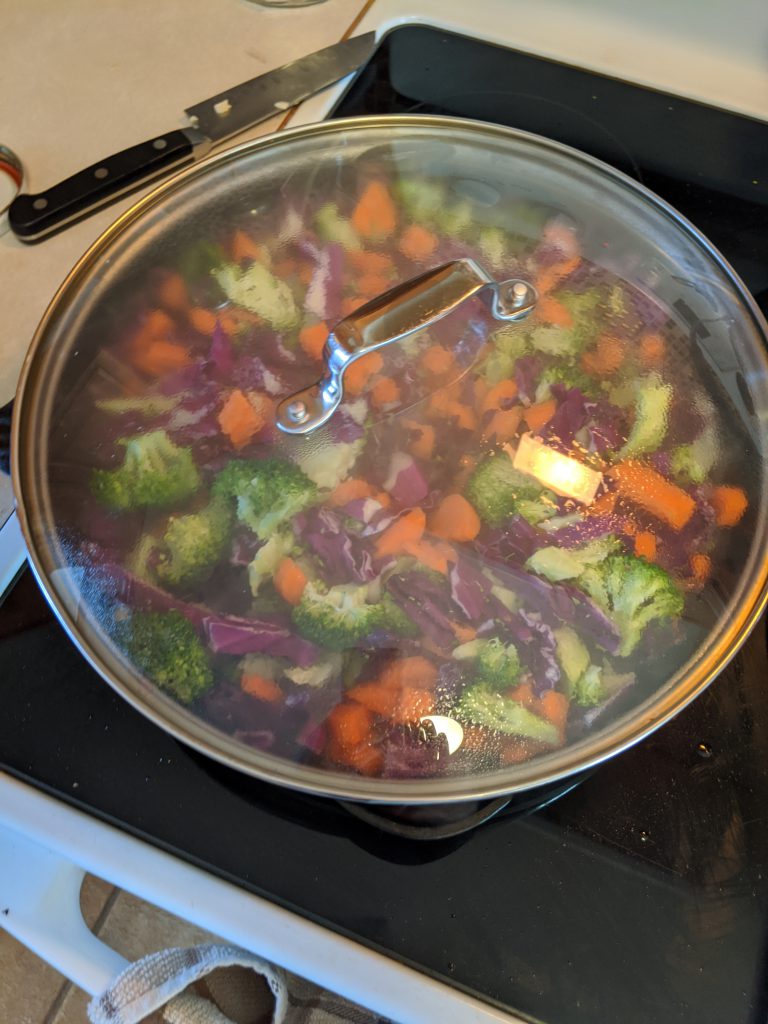 carrots, cabbage and broccoli in cast iron pan with glass lid - steamy