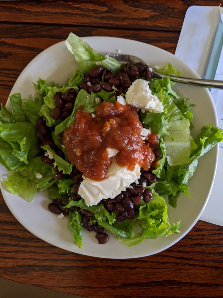lettuce, black beans, salsa, scoop of queso fresco in a white dish