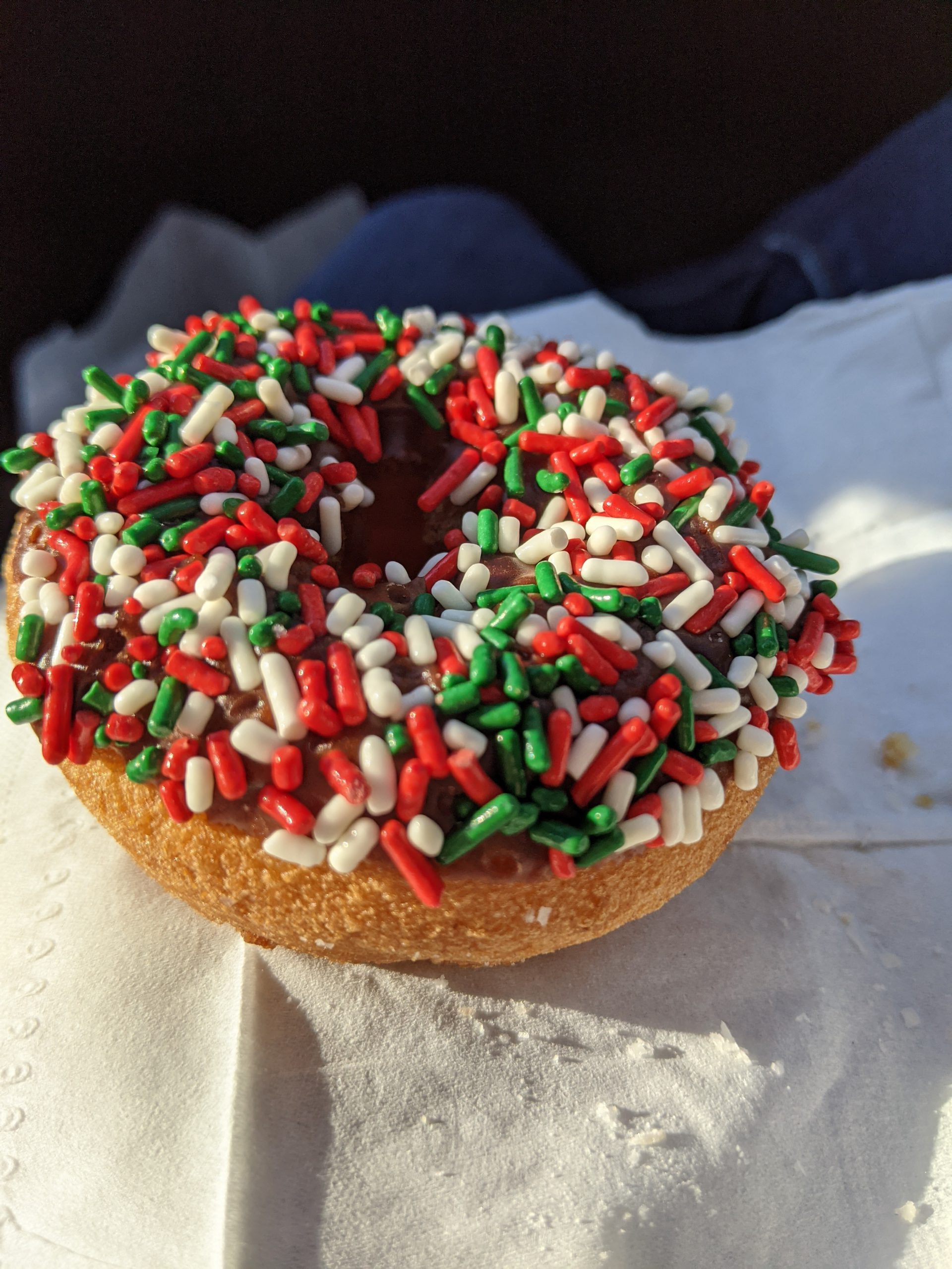 Donut with red, white, and green sprinkles on a paper napkin