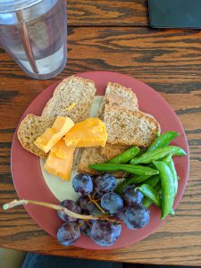 plate with bread, cheese, grapes, and snap peas