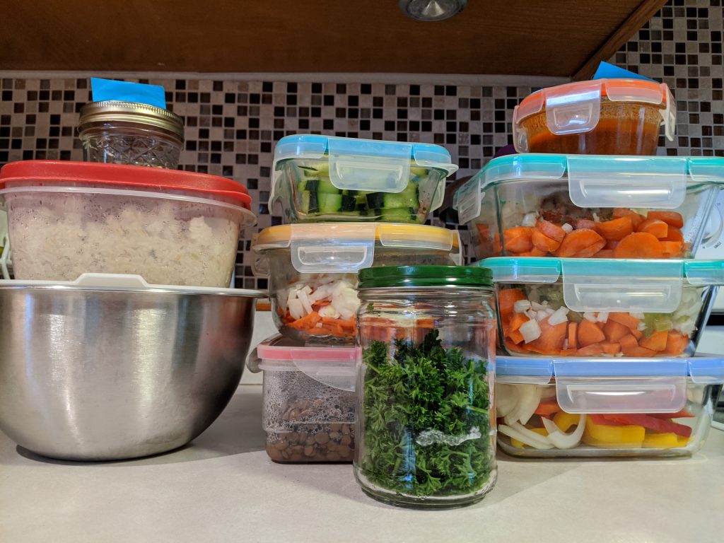 Stack of glass containers containing prepared, colorful foods