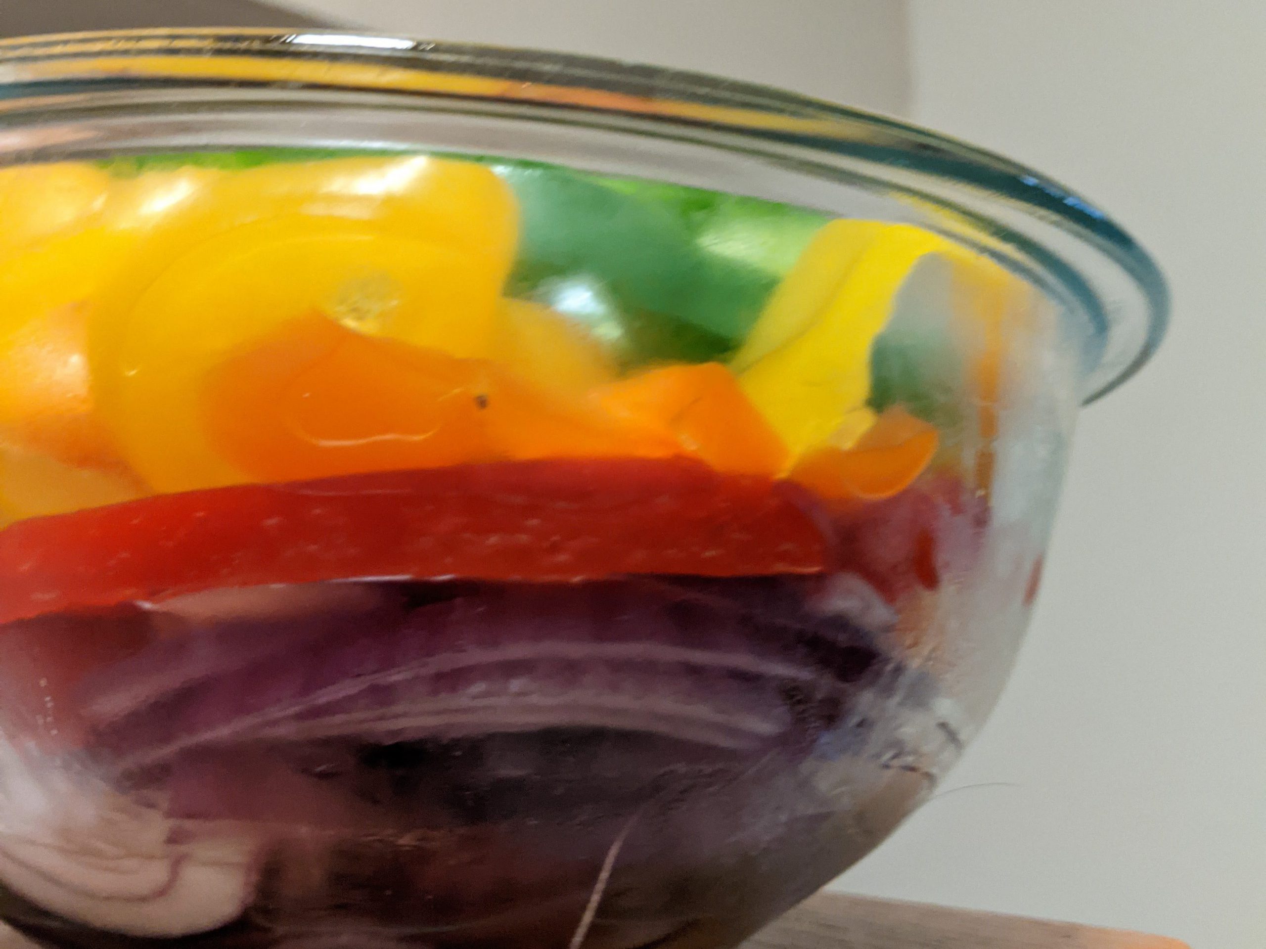 a blurry photo of a glass bowl of colorful bell peppers.