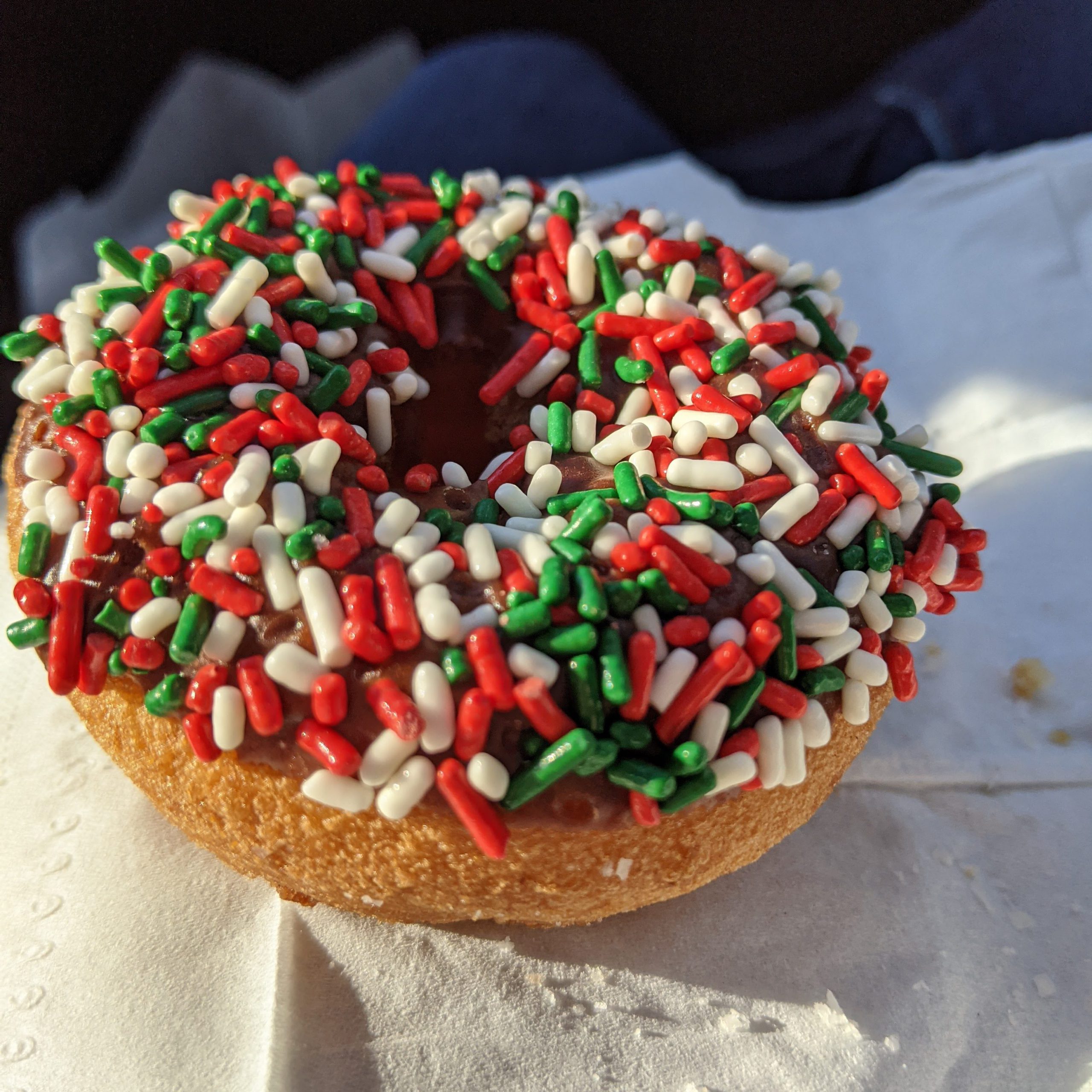 A donut with red white and green sprinkles