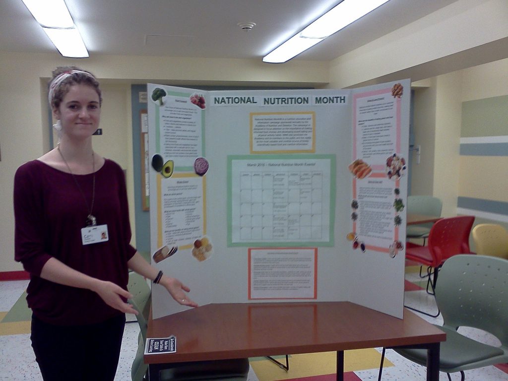 Woman stands in front of national nutrition month poster board