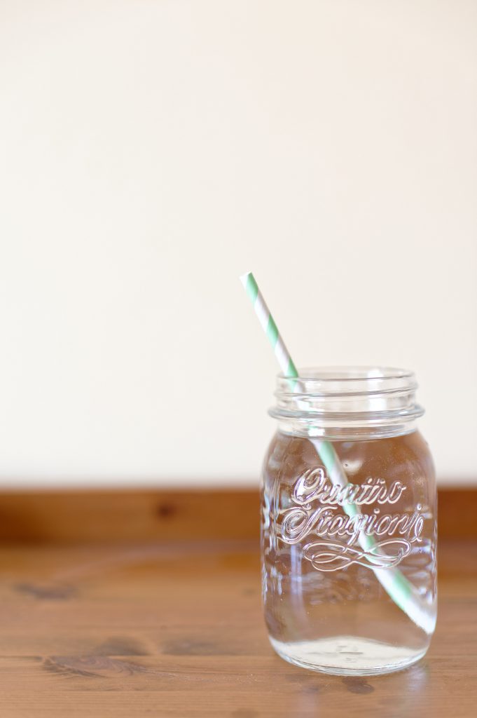 mason jar full of water with a striped straw