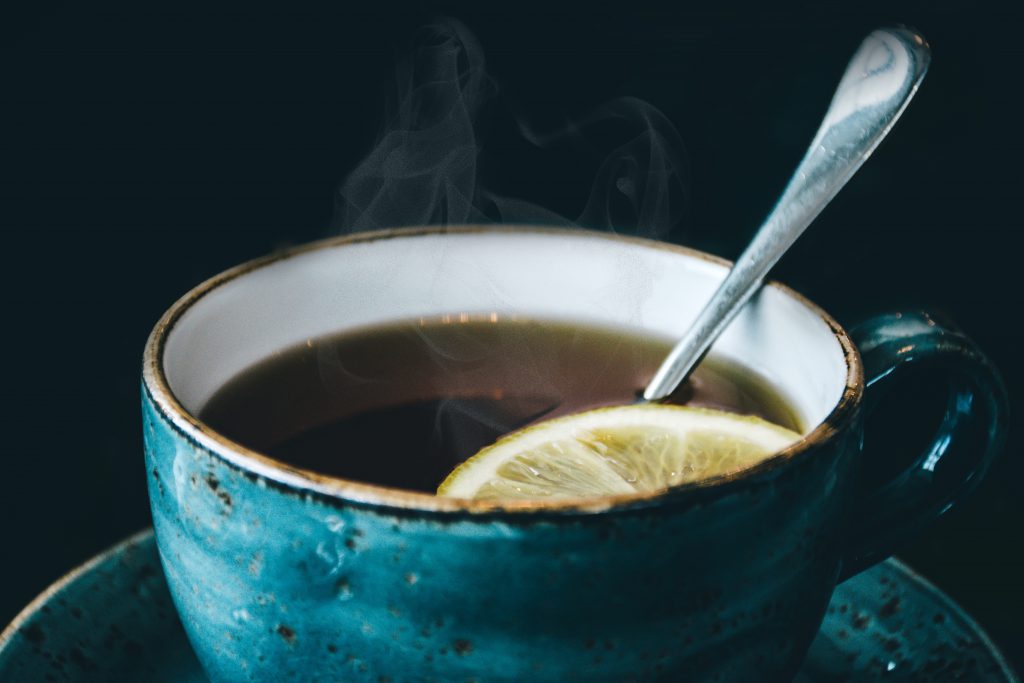 Steaming tea with lemon in a blue teacup with spoon